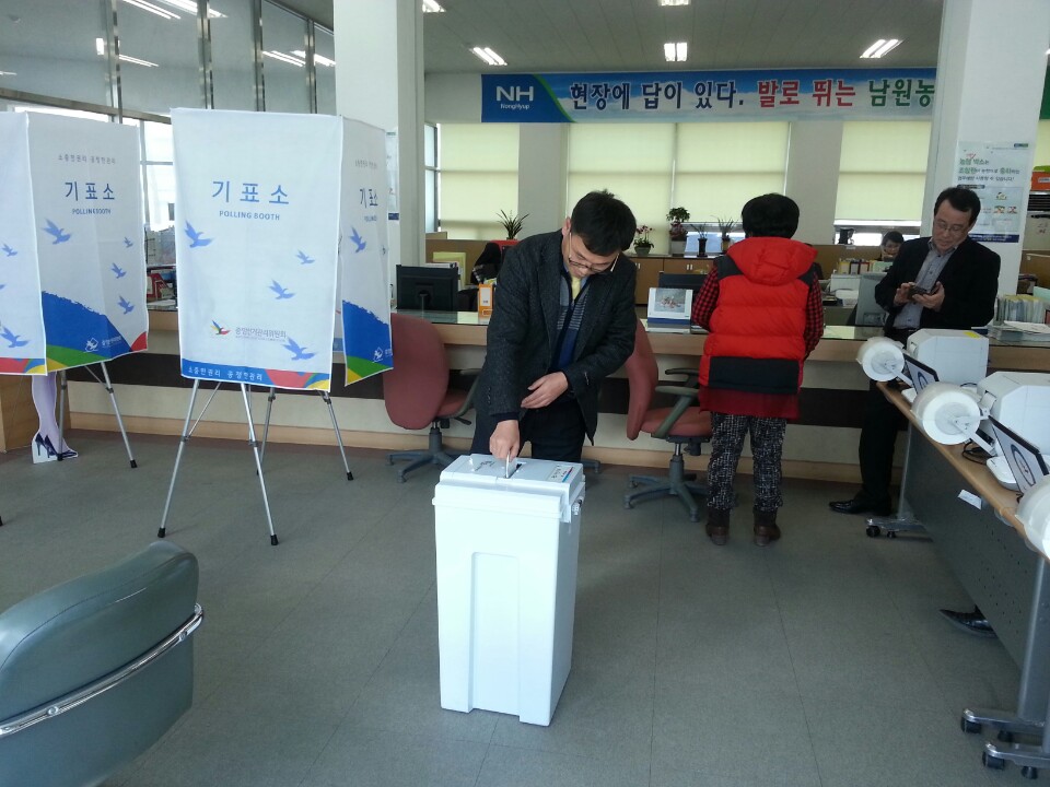 모의투표 체험 참가자가 기표한 모의 투표용지를 투표함에 투입하고 있는 모습